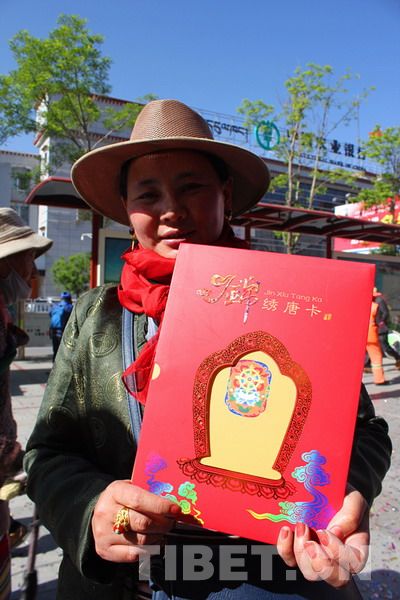 一位藏族群众手持《唐卡》特种邮票